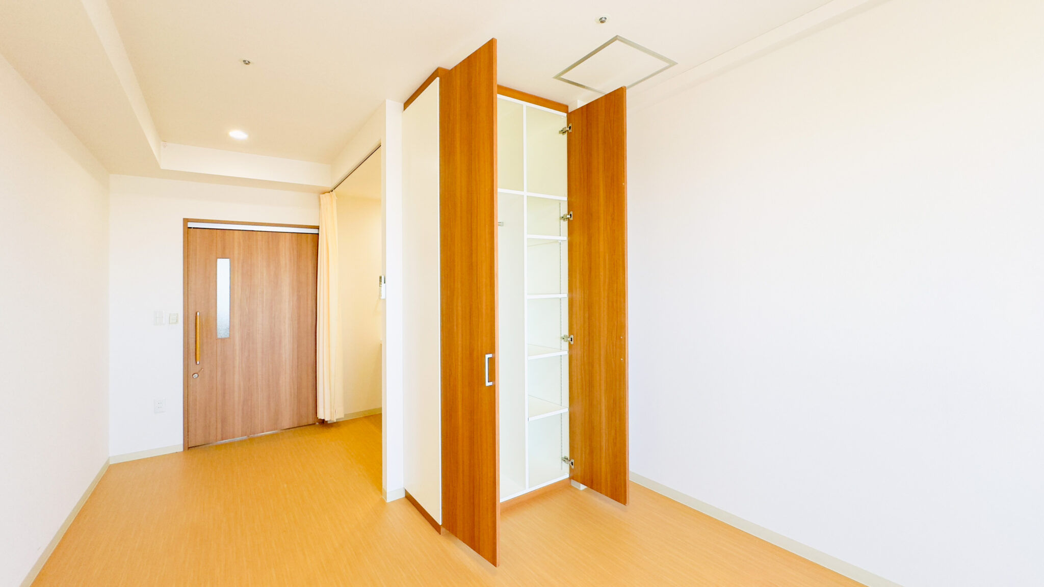 木製建具と明るい内装の居室入口。採光良好でモダンな設計の空間。